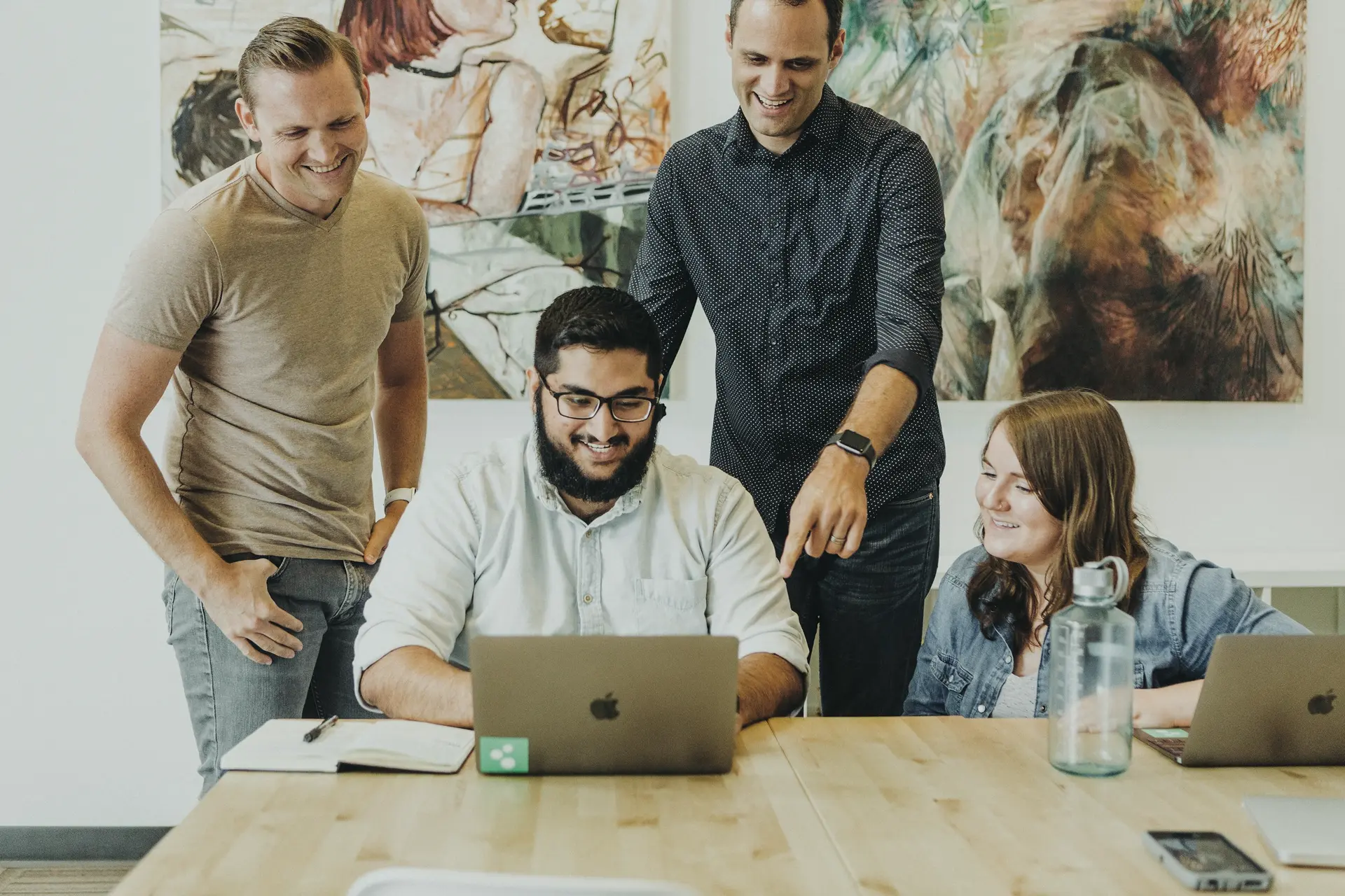 Colleagues smiling around a laptop
