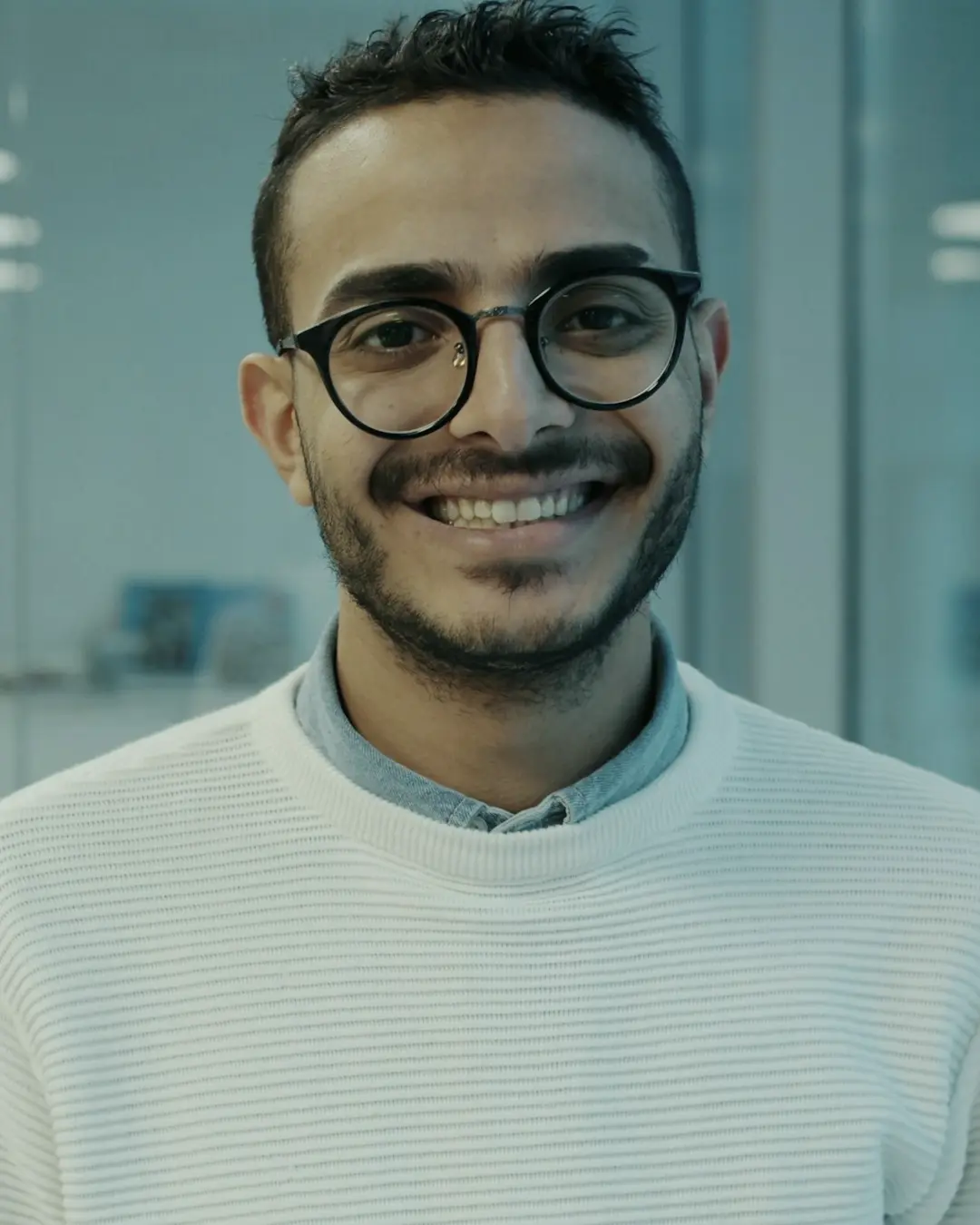 A smiling engineer in glasses in a modern office