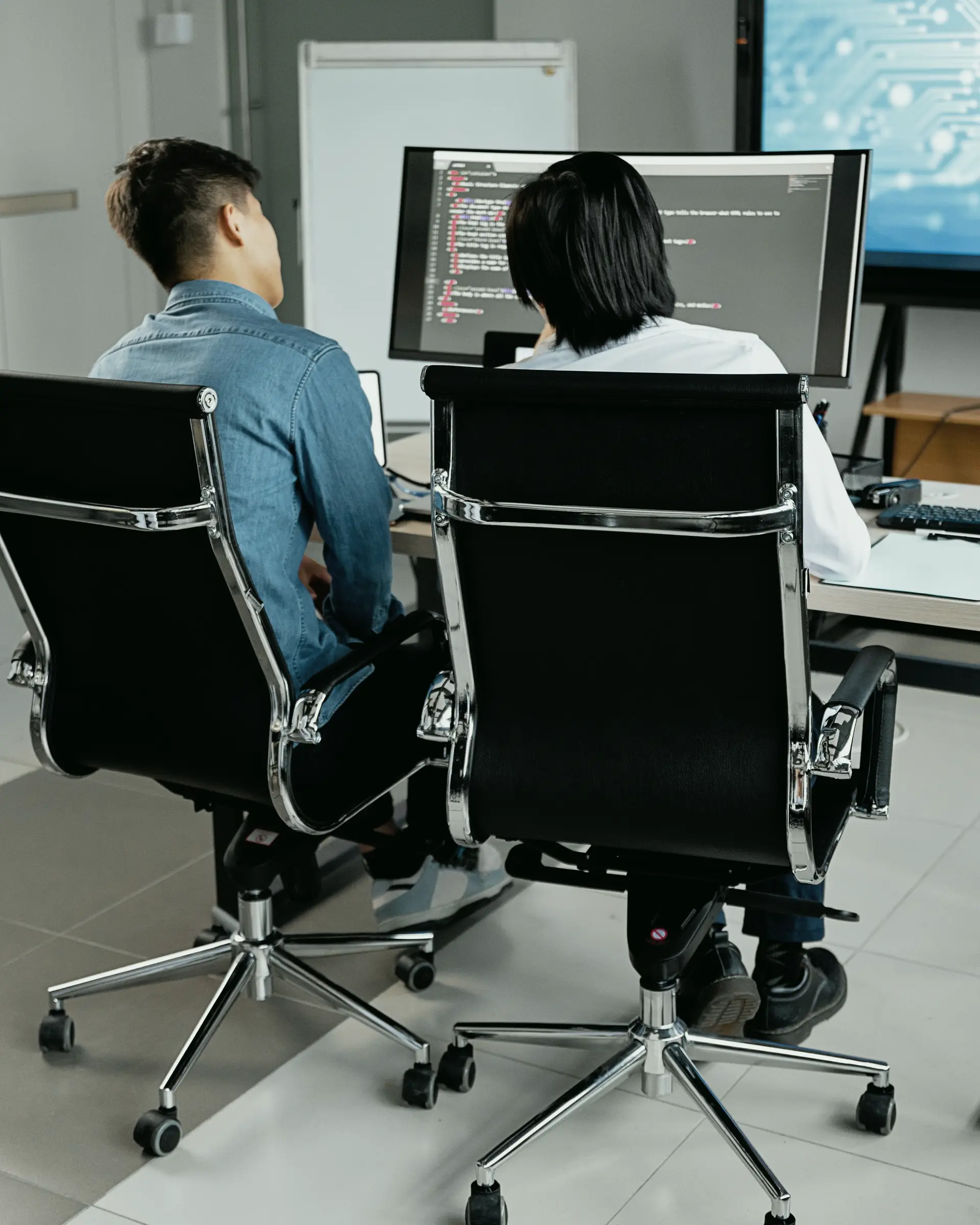 Two engineers working side by side at screens of code