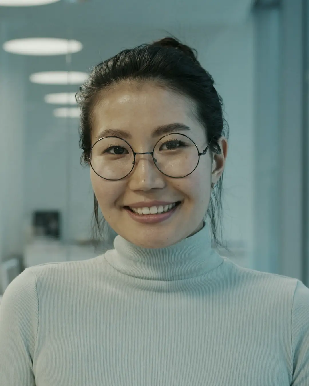 A smiling engineer in glasses in a glass-walled office
