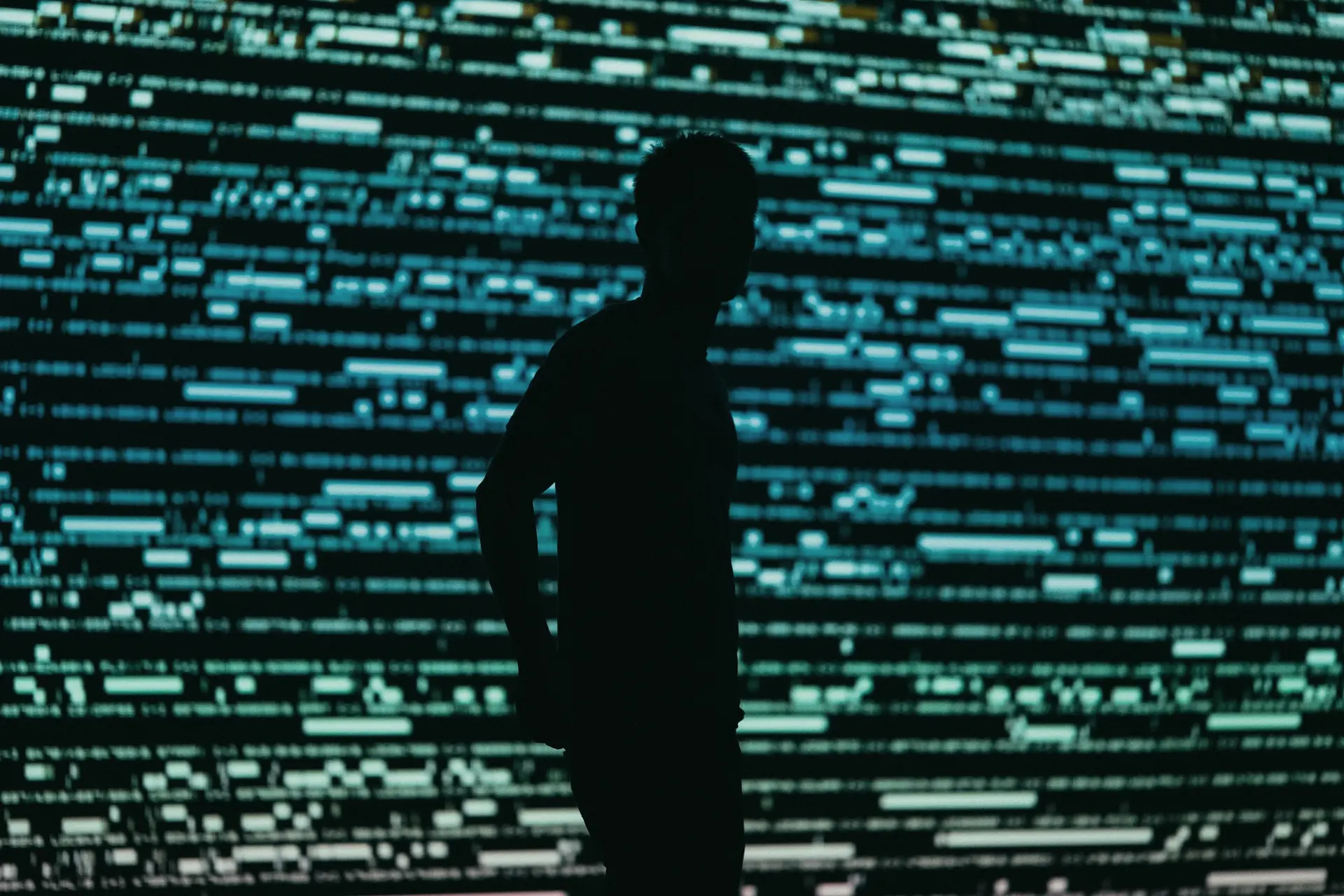 An analyst silhouetted against a wall of streaming data